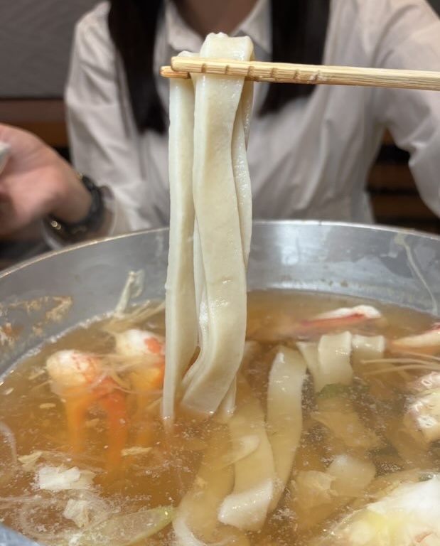 かにしゃぶのシメに極太うどんを食べる様子